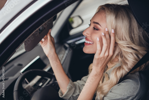 Photo of adorable satisfied lady sitting car driver seat adjust look mirror touch face