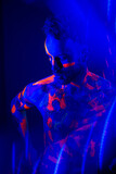 Portrait of a man with ultraviolet makeup and neon light in cyberpunk style.