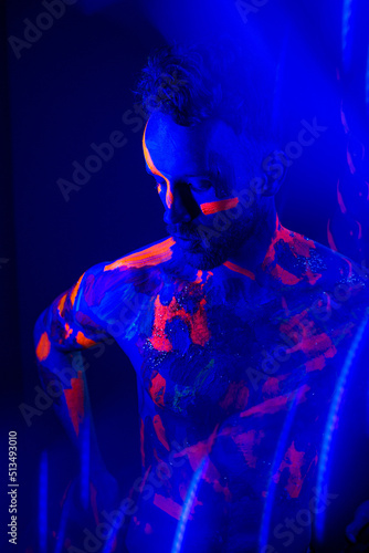 Portrait of a man with ultraviolet makeup and neon light in cyberpunk style.