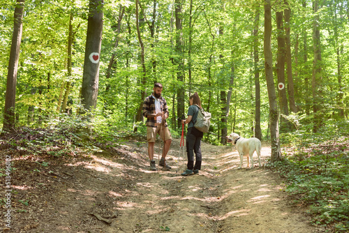 Young happy couple and their dog at hiking through the woods enjoying the sight. Two nature lovers in the mountain forest enjoy healthy walking through the nature. With film grain © Srdjan