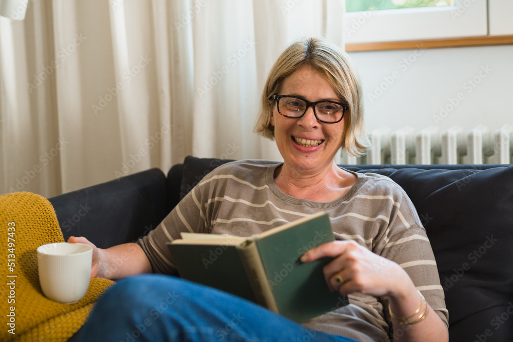 smiling adult woman reading book. looking at camera smiling adult woman reading book. looking at camera