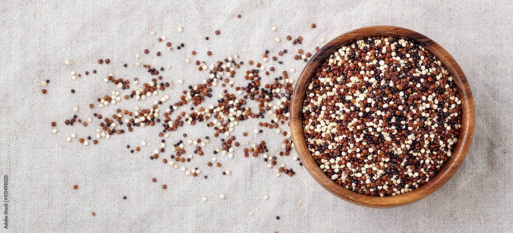 Red, black and white quinoa in wooden bowl on linen cloth background Red, black and white quinoa in wooden bowl on linen cloth background