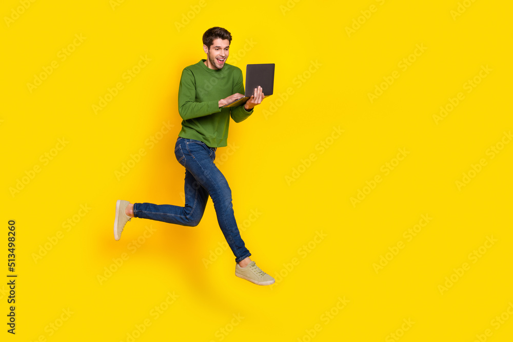 Photo of sweet attractive guy dressed green pullover jumping chatting modern gadget empty space isolated yellow color background Photo of sweet attractive guy dressed green pullover jumping chatting modern gadget empty space isolated yellow color background