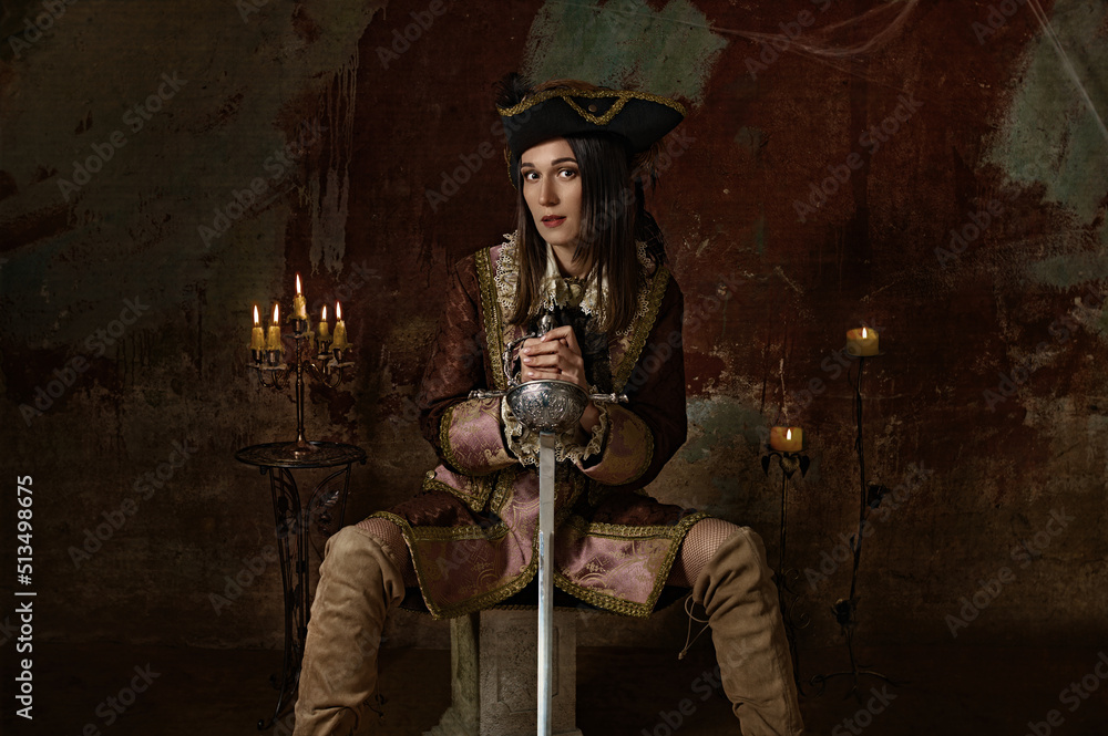 retro portrait of a musketeer girl in a hat with a sword.