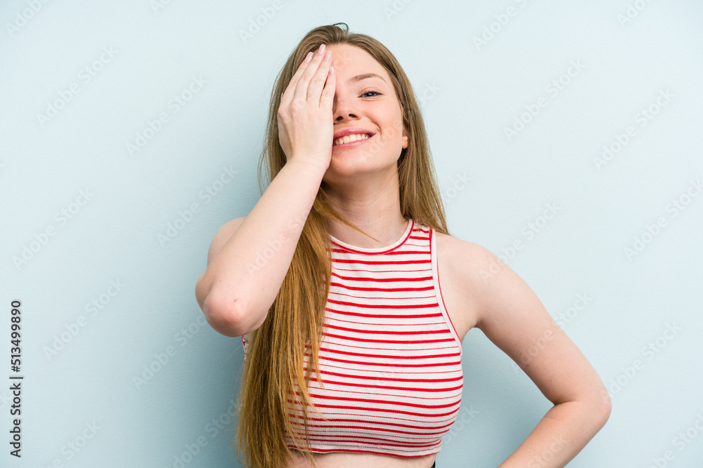 Young caucasian woman isolated on blue background having fun covering half of face with palm. Young caucasian woman isolated on blue background having fun covering half of face with palm.
