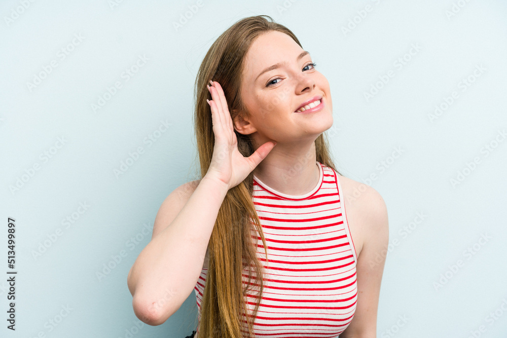 Young caucasian woman isolated on blue background trying to listening a gossip. Young caucasian woman isolated on blue background trying to listening a gossip.