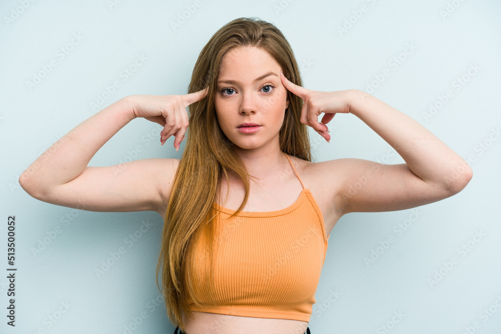 Young caucasian woman isolated on blue background focused on a task, keeping forefingers pointing head. Young caucasian woman isolated on blue background focused on a task, keeping forefingers pointing head.