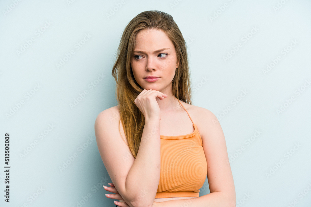 Young caucasian woman isolated on blue background suspicious, uncertain, examining you. Young caucasian woman isolated on blue background suspicious, uncertain, examining you.