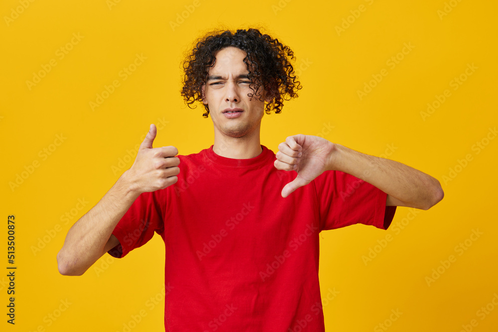 Dissatisfied funny Caucasian young man in red t-shirt show Dis Like gesture posing isolated on yellow studio background. The best offer with free place for advertising. Emotions for everyday concept Dissatisfied funny Caucasian young man in red t-shirt show Dis Like gesture posing isolated on yellow studio background. The best offer with free place for advertising. Emotions for everyday concept