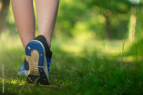 A beautiful close-up for a lifestyle, outdoor sporting activity. Women's feet in sneakers against a green forest in snowy weather.