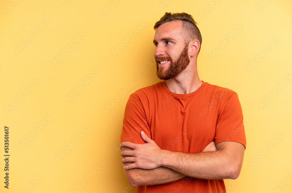 Young caucasian man isolated on yellow background smiling confident with crossed arms. Young caucasian man isolated on yellow background smiling confident with crossed arms.