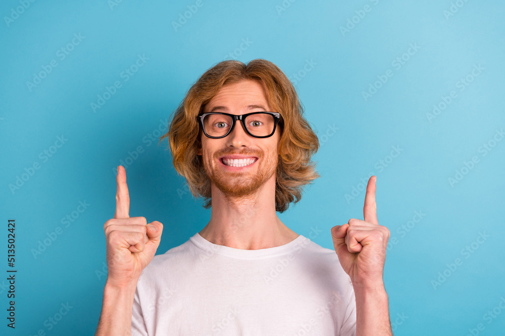 Portrait of positive cheerful guy indicate fingers up empty space blank banner isolated on blue color background Portrait of positive cheerful guy indicate fingers up empty space blank banner isolated on blue color background