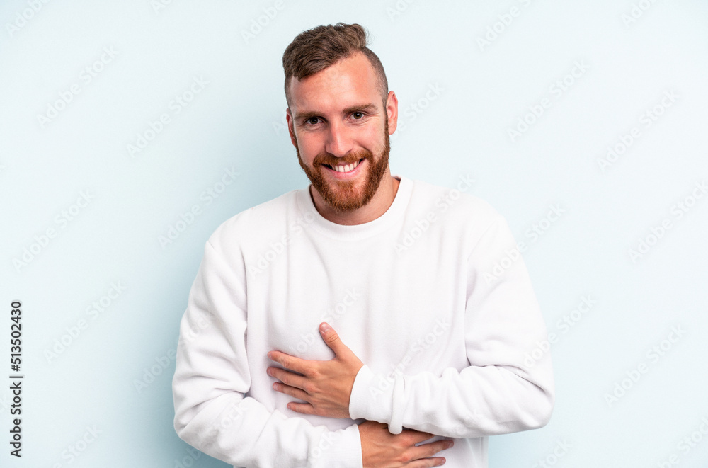 Young caucasian man isolated on blue background laughing and having fun. Young caucasian man isolated on blue background laughing and having fun.