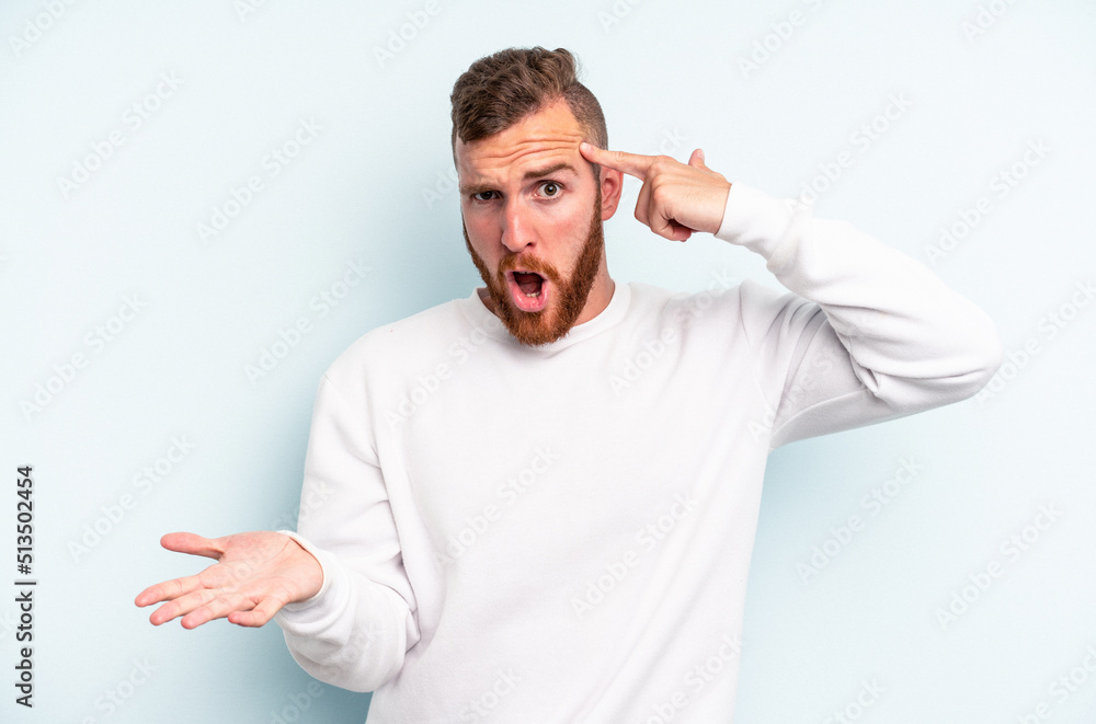 Young caucasian man isolated on blue background holding and showing a product on hand. Young caucasian man isolated on blue background holding and showing a product on hand.
