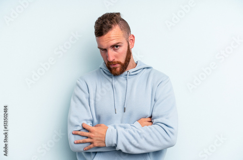 Young caucasian man isolated on blue background who is bored, fatigued and need a relax day.