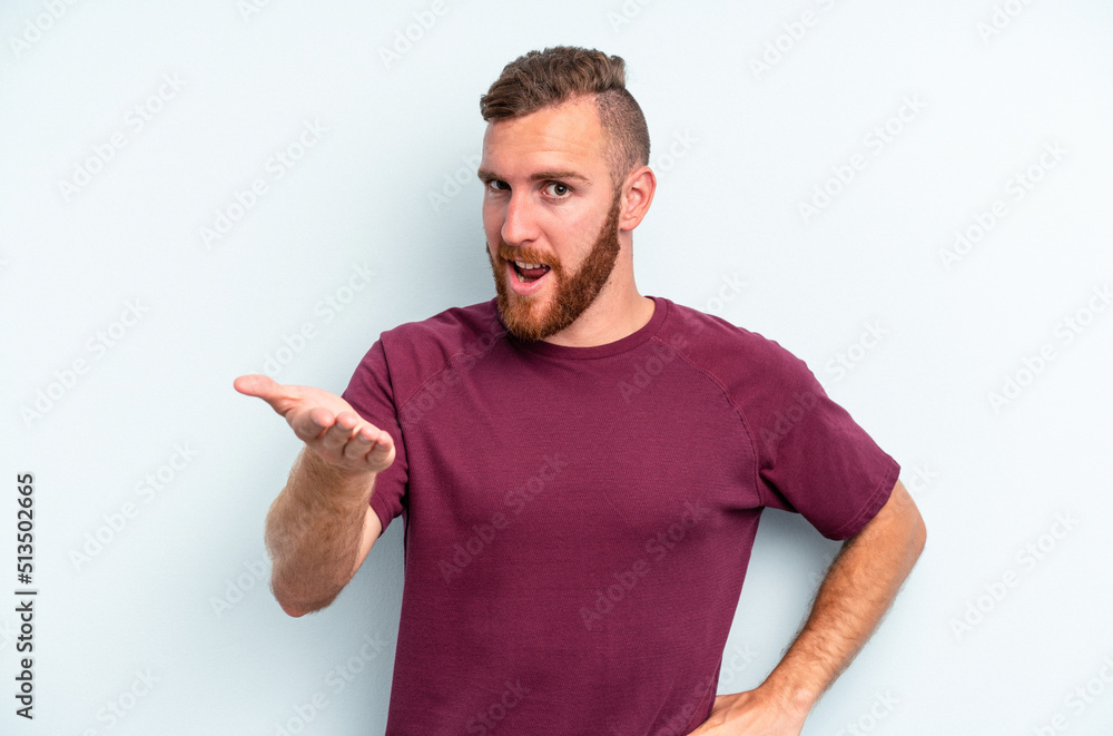 Young caucasian man isolated on blue background stretching hand at camera in greeting gesture. Young caucasian man isolated on blue background stretching hand at camera in greeting gesture.
