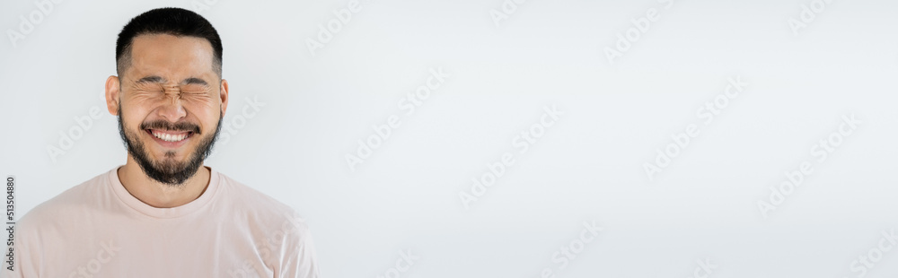 Fototapeta premium portrait of asian man with beard and closed eyes smiling isolated on grey, banner.