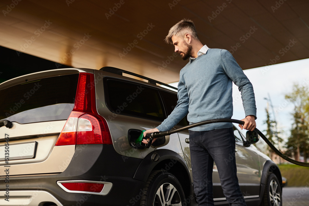 Young confident man refueling off road car at gas station