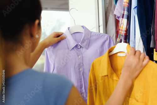 Fotografie Woman comparing clothes in her wardrobe
