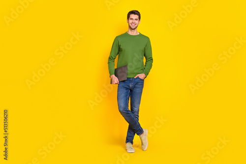Photo of funny attractive guy wear green sweater holding modern gadget empty space isolated yellow color background