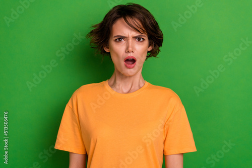 Photo of impressed shocked young woman dressed orange listening bad news open mouth isolated green color background