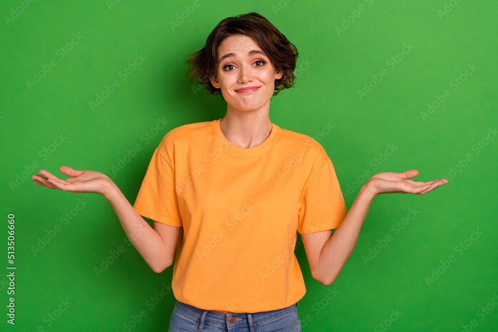 Photo of doubtful funny young woman dressed orange t-shirt shrugging shoulders isolated green color background Photo of doubtful funny young woman dressed orange t-shirt shrugging shoulders isolated green color background