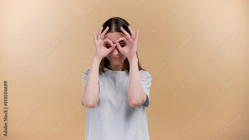 Cheerful young caucasian girl with a smile playing ful at the camera plaine beige background. Cheerful young caucasian girl with a smile playing ful at the camera plaine beige background.
