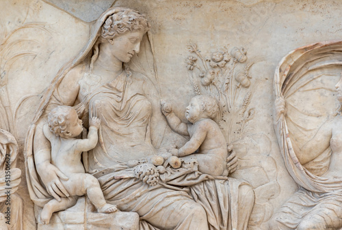 Beautiful woman holding twin babies carved in ancient roman marble wall