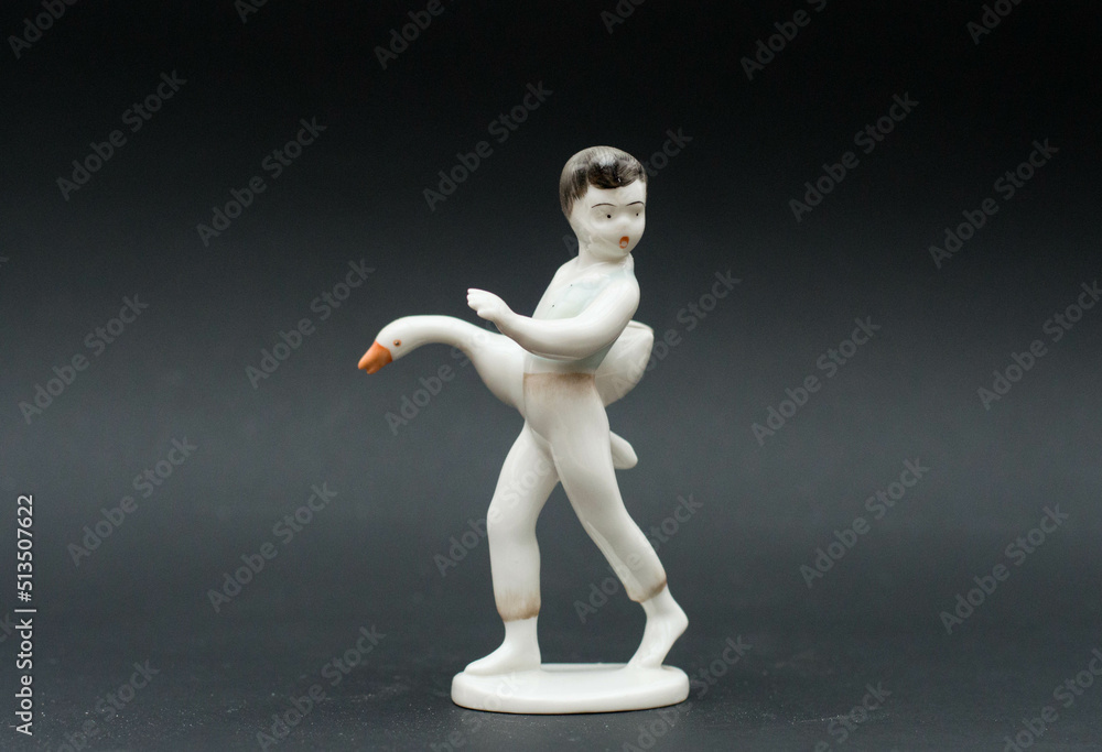 Mid-century modern porcelain figurine - little boy stealing a duck - isolated on black background Mid-century modern porcelain figurine - little boy stealing a duck - isolated on black background