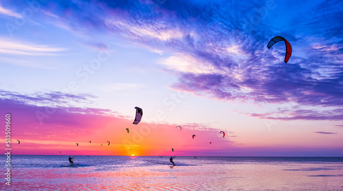 Kite-surfing against a beautiful sunset. Many silhouettes of kites in the sky. Holidays on nature. Artistic picture. Beauty world.