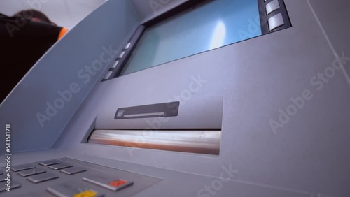 Woman's hand takes banknotes out of ATM in bank or room. Public place. . concept of finance, money, bank and people - close-up of hand withdrawing cash from ATM. Cashing out currency or money. photo