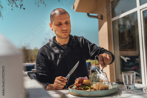 A man is eating burger outdoors during the day