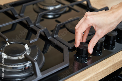 Female hand adjusting temperature on gas hob control panel, Woman using gas stove, Modern household appliances