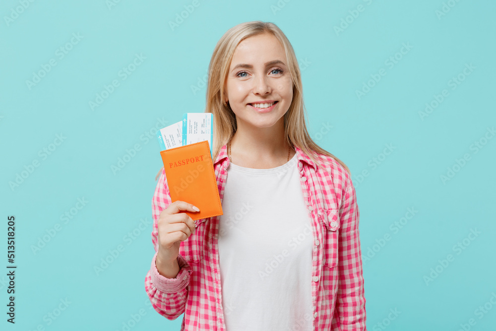 Traveler tourist woman wear casual clothes hold passport boarding tickets isolated on plain pastel light blue background studio. Passenger travel abroad on weekends getaway Air flight journey concept Traveler tourist woman wear casual clothes hold passport boarding tickets isolated on plain pastel light blue background studio. Passenger travel abroad on weekends getaway Air flight journey concept