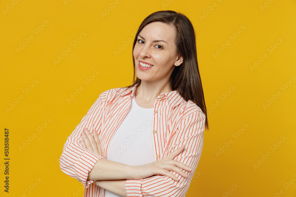 Young cheerful fun happy smiling woman she 30s wears striped shirt white t-shirt look camera hold hands crossed folded isolated on plain yellow background studio portrait. People lifestyle concept Young cheerful fun happy smiling woman she 30s wears striped shirt white t-shirt look camera hold hands crossed folded isolated on plain yellow background studio portrait. People lifestyle concept
