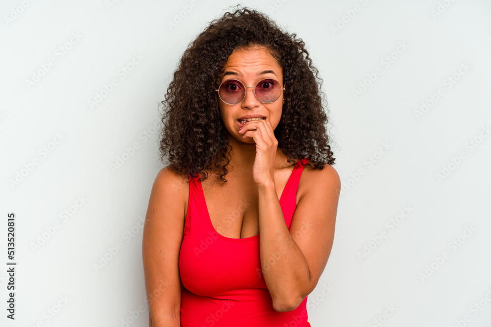 Young brazilian woman wearing a swimsuit isolated on blue background biting fingernails, nervous and very anxious. Young brazilian woman wearing a swimsuit isolated on blue background biting fingernails, nervous and very anxious.