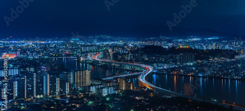 Bird s eye view of a night panorama cityscape of Fukuoka with the illuminated urban expressway circular route crossing in zig-zag the Muromi river taken from the observation deck of Fukuoka Tower.