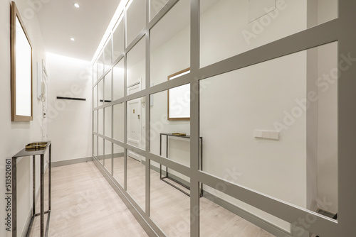Narrow hallway in a home with an industrial-style appliance and a wall covered in gray-edged mirrors