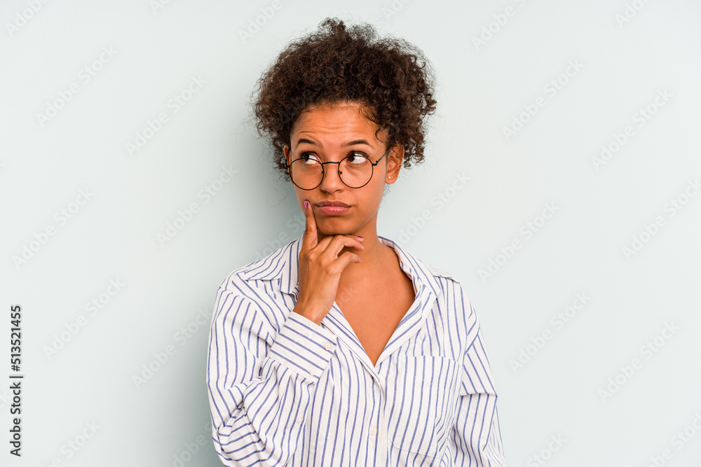 Young Brazilian woman isolated on blue background contemplating, planning a strategy, thinking about the way of a business. Young Brazilian woman isolated on blue background contemplating, planning a strategy, thinking about the way of a business.