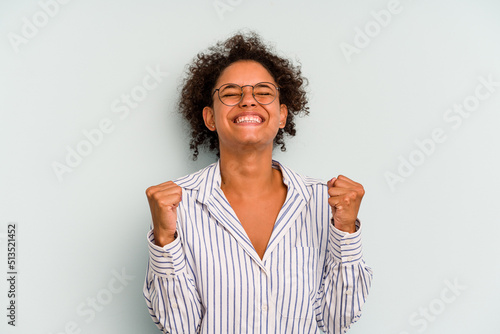 Young Brazilian woman isolated on blue background celebrating a victory, passion and enthusiasm, happy expression.