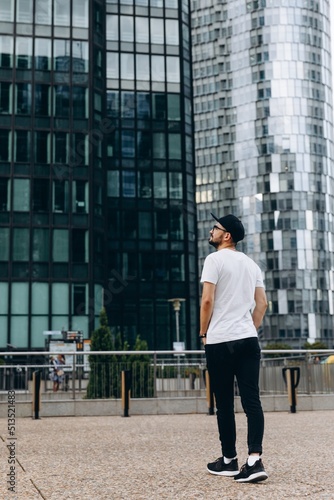 Stylish young man admires the large glass skyscrapers. Feels like a businessman. Business and man concept between skyscrapers.
