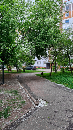 Sidewalk at the suburb that goes through blooming trees. Residential district with old soviet habitation. Path for a walk with no people around in the native neighborhood.