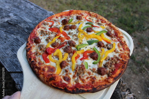 Pizza merguez, poivrons, viande hachée sur planche en bois photo