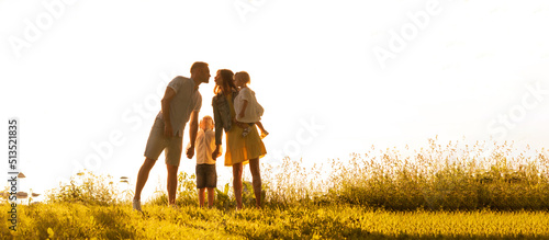 Happy loving family walking outdoor in the light of sunset. Father, mother, son and daughter.