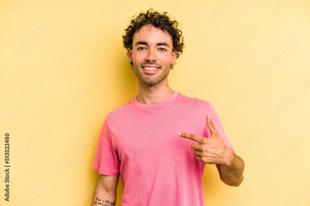Obraz premium Young caucasian man isolated on yellow background person pointing by hand to a shirt copy space, proud and confident