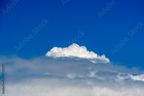 Heavy white lone cumulus cloud against blue summer sky.