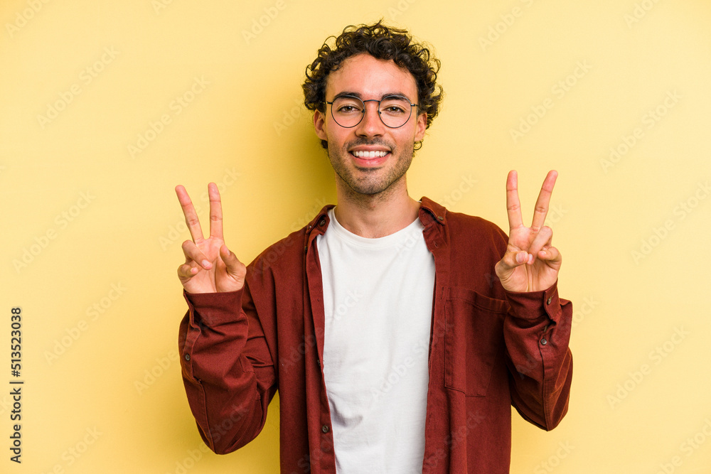 Young caucasian man isolated on yellow background showing victory sign and smiling broadly. Young caucasian man isolated on yellow background showing victory sign and smiling broadly.