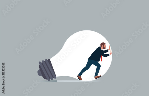 Strong businessman inside light bulb trying to get out.