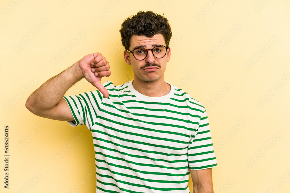 Young caucasian man isolated on yellow background showing a dislike gesture, thumbs down. Disagreement concept. Young caucasian man isolated on yellow background showing a dislike gesture, thumbs down. Disagreement concept.