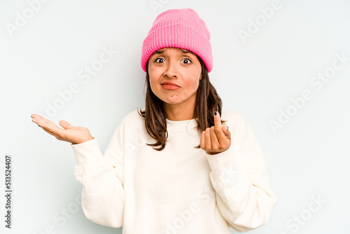 Young hispanic woman isolated on blue background pointing to different copy spaces, choosing one of them, showing with finger.